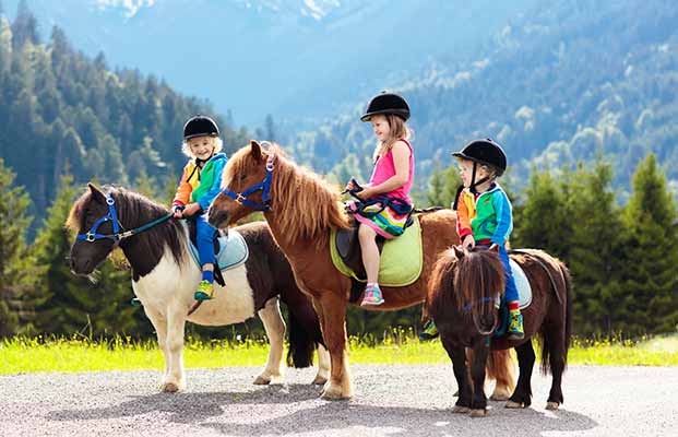 Tre bambini in sella ai pony