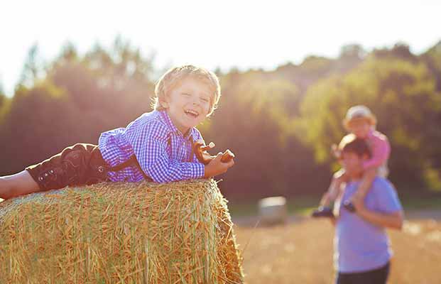 Padre e figli si divertono su una balla di paglia