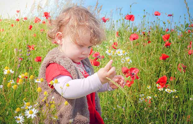 Bambino seduto in un prato fiorito